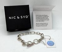 Bracelet with box and a small information card showing brand philosophy and quality assurance tag.