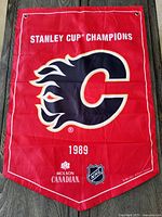 Full view of red 1989 Calgary Flames Stanley Cup Champions banner featuring large flaming C logo and championship text.