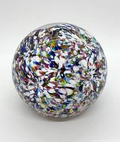 Top-down view of spherical multicolor Italian paperweight showing flower-like indentations in the glass pattern.
