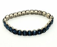 Close-up view of the bracelet coiled to display front with deep blue baguette-cut crystals set in silver-tone links.