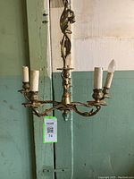 Full view of the antique brass chandelier showing its overall structure with five arms and candle-style lights.