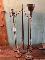 Five antique floor lamps placed together showing overall designs and condition.