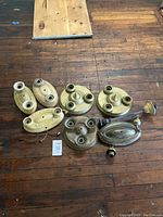 Eight antique flush mount ceiling light fixtures laid out on wooden floor, showing full lot view.