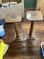 Top view of two antique oak stands showing square tops with wear and discoloration, column supports, and square bases