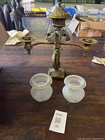 Brass lamp base with dual arms and two glass shades positioned at front