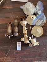 Seven ceiling light fixtures including porcelain flush mount bases, porcelain stem fixtures, and glass stem fixtures arranged on a wooden floor.