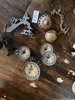 Cast iron wall bracket, single font holders and decorative finials all laid out on a wooden surface showing condition and details of the cast metal parts.