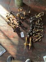Photo showing assorted lamp clusters and metal fittings on wooden floor including multiple socket arms and metal hooks.
