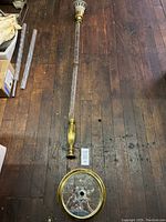 Full lamp layout showing glass stem section, brass fittings on top and bottom, and round mirror base with brass rim.