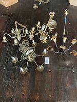 Four vintage tole chandeliers laid out on dark wood floor showing overall size and design