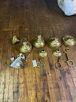 Overview of all items in the lot including three bronze fixtures and loose extra bolts, finials and fittings arranged on wooden floor.