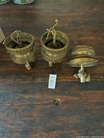 Three bronze flush mount electric light fixtures arranged on a wooden floor, showing wiring and the base design.