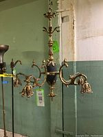 Full view of the brass chandelier showing five arms with detailed ornamentation and bulb holders with leaf motifs.