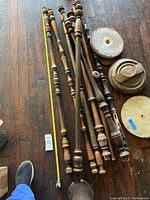 Wooden lamp stems laid on wooden floor with measuring tape showing size approximately 50 inches long