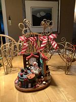 Two gold wireframe reindeer with striped bows placed on a wooden table with a framed picture in background.