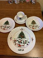 Holiday dish set showing cup, saucer, side plates, and dinner plate with Christmas tree holiday village design.
