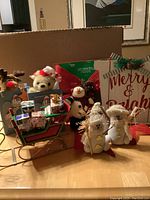 View of the wooden sleigh, LED lighted bow, wooden gift boxes with teddy bears, fabric snowmen, and Merry & Bright shelf sitter