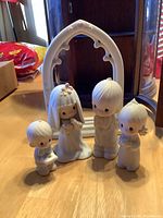 Front view of the five-piece Precious Moments wedding figurine set showing bride, groom, ring bearer, flower girl, and white arch.