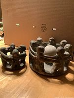 Two stone friendship circle candle holders, the larger one with 12 figures and smaller one with 6 figures, both carved from heavy stone showing detailed human figures holding hands.