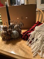Overall photo showing metal basket containing gourds and two throw blankets on table