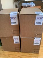 Four large closed cardboard master cartons stacked, each labeled as containing 1000 coin wrappers per box.