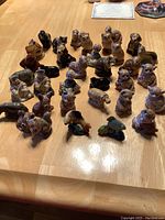 Front view of most of the 35 Wade tea figurines on a wooden table highlighting variety of animals including multiple dogs and bears, visible painted details and glaze.