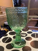 Single green tinted glass goblet with embossed sunflower-like pattern and textured stem, set on a Bowring branded surface.