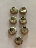 Set of 7 silver metal Coca Cola bottle caps with original cork backing featuring black and white portraits of NHL hockey players from 1964.