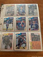 Photo showing nine 1983/84 OPC cards in binder, featuring players from Edmonton Oilers and Boston Bruins among others, including Wayne Gretzky.