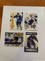 Four hockey cards placed on flat white background, each signed by respective players in ink.