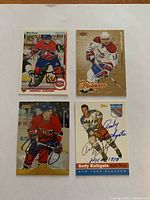 Four autographed hockey cards laid out on white background: Mike Bossy, Pierre Pichanec, Guy Lafleur, Andy Bathgate.