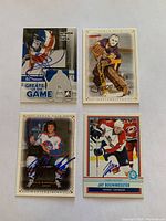 Photo showing all four autographed hockey cards laid out in two rows, with visible player signatures and team uniforms.