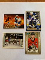 Four hockey cards arranged in two rows, each card autographed by a different player.