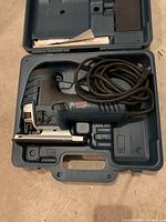 Bosch electric jigsaw inside carrying case with power cord coiled and manual included, tool blade missing