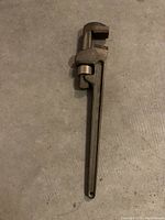 Full view of the brass pipe wrench showing its length and adjustable jaw.