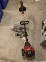 Full view of Craftsman gas trimmer showing handle, shaft, and trimmer head, with some accessories and packaging in the background.