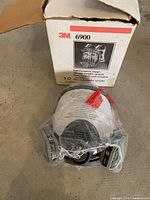 3M 6900 full facepiece respirator sealed in plastic in front of its original box, showing product packaging and branding.