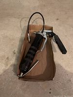 Manual grease gun tool placed in a cardboard tray showing overall condition and design.