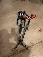Full view of safety harness laid flat on floor showing straps and lanyard attached.