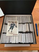 Shoebox filled with organized hockey cards and an exposed card of Ryan Smyth from Upper Deck 1995-96 series.