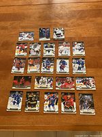Full lot of 22 hockey cards arranged on wood floor, showing varied players and teams.