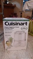 Original box of the Cuisinart frozen yogurt, ice cream and sorbet maker. Box displays product branding, product name, and images of desserts made with the machine.
