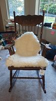 Front view of the large wooden rocking chair showing the detailed carved headrest and plush seat cover