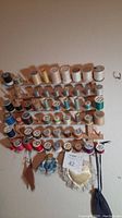 Full view of wooden rack mounted on wall with numerous spools of thread in different colors and sizes.