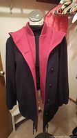 MacKintosh vestcoat jacket in black and red colors on mannequin, showing front button closure and collar.