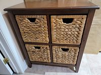 Wood storage cabinet with four woven basket drawers inside a wooden frame finish in dark brown color.