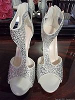 Front view of the white bridal sandals showing crystal decorations and open toe design.