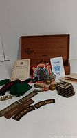 Several Canadian military and collectible items displayed in front of a wooden box labeled 'Galaxy Edmonton' with associated documents, badges, pins, patches and small brass collectibles.