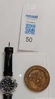 Photo of Stauer watch and US Military Academy bronze table coin side by side with MaxSold tag 50