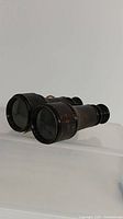 Side view of the vintage Lemayre binoculars showing black metal body and glass lenses.